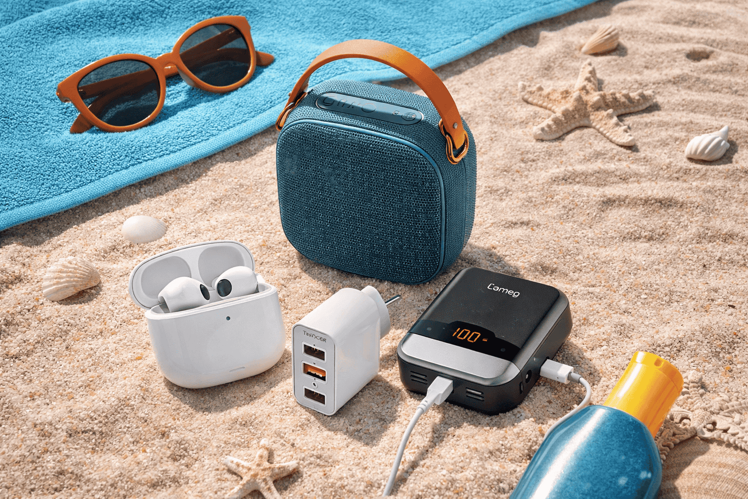 Gadgets de verano en playa: parlante portátil, powerbank y audífonos sobre arena para la colección Verano Tech de High Tech Store.